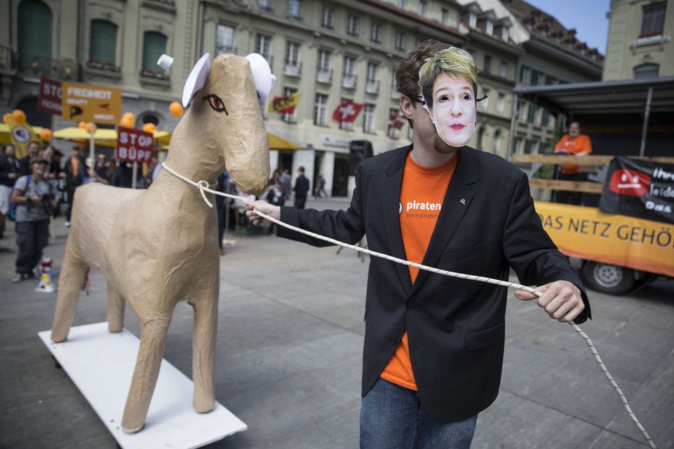 Ein Demonstrant mit einer Simonetta Sommaruga-Maske schleppt ein Trojanisches Pferd über den Bundesplatz.